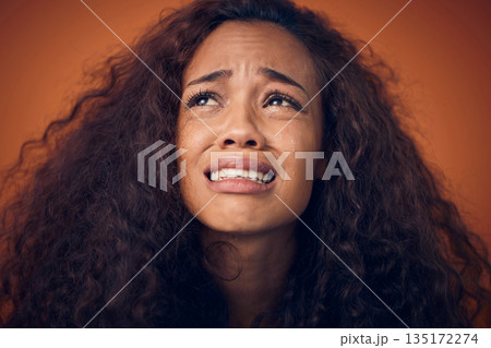 Woman, crying and sad face in studio with anxiety, mental health problem and depression. Headshot of african female person on a brown background for cry emoji, psychology and broken heart with tears 135172274