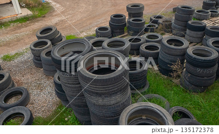 Stacked used tires outside on the grass Stacked used tires outside on the grass 135172378