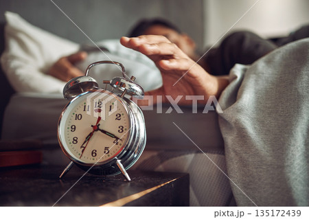 Alarm clock, wake up and man sleeping in the bedroom of his modern apartment in the morning. Lazy, resting and hand of male person taking a nap and dreaming in bed with time watch at his home. 135172439