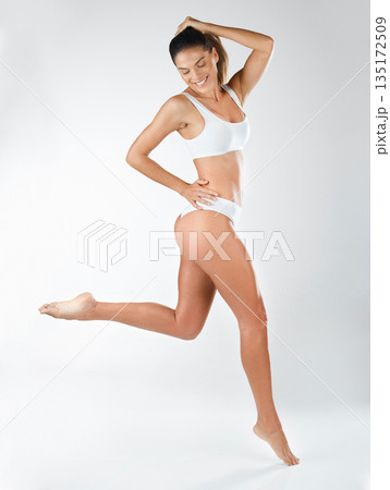 Jump, healthy and a happy woman and active in underwear isolated on a white background in a studio. Smile, carefree and a young lady in a bikini, jumping with happiness or wellness on a backdrop 135172509