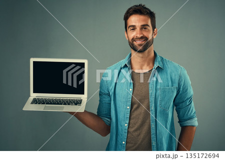 Happy man, laptop and mockup screen for advertising or marketing against a grey studio background. Portrait of male person with smile showing computer display or mock up space for advertisement 135172694