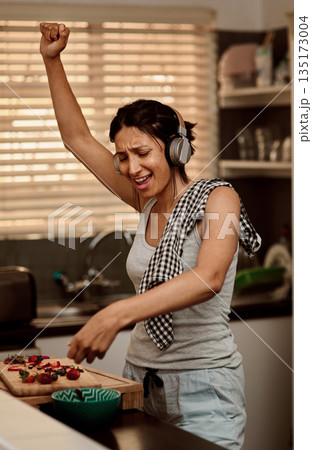 Music headphones, singing and woman cooking with strawberry. Sing, kitchen and female person making snack with fruit for healthy nutrition while dancing to audio, sound and radio podcast in home. Music headphones, singing and woman cooking with strawberry. Sing, kitchen and female person making snack with fruit for healthy nutrition while dancing to audio, sound and radio podcast in home. 135173004