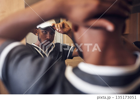 Baseball player, cap and face of sports man in a locker room getting ready and dressing in mirror. Behind an African athlete person with reflection and hat for sport competition, training or exercise 135173051