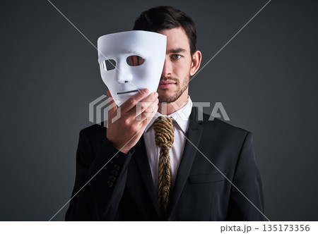 Two faces, holding mask and businessman portrait in a studio with serious face with secret and fraud. Worker or corporate criminal with rope tie showing identity theft or liar in business suit mockup Two faces, holding mask and businessman portrait in a studio with serious face with secret and fraud. Worker or corporate criminal with rope tie showing identity theft or liar in business suit mockup 135173356