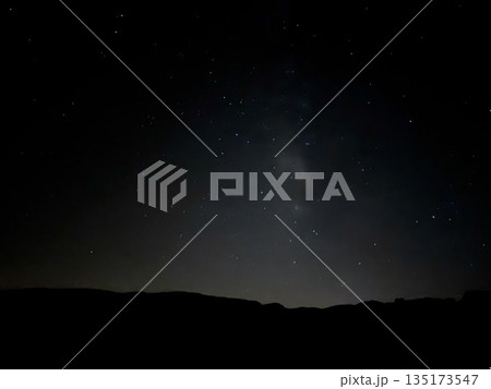 Long exposure photo of the Milky Way arching over dark volcanic mountains at night near Teide Observatory, Tenerife. 135173547
