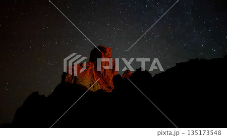 Volcanic rock formation illuminated with red light beneath a clear starry sky in Teide National Park at night. 135173548