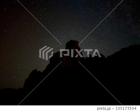 Dark silhouette of volcanic formations beneath a star-filled sky in Teide National Park, Tenerife, captured at night. 135173554