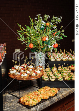 Wide shot of buffet table with canapes and croissants - elegant presentation for event Wide shot of buffet table with canapes and croissants - elegant presentation for event 135174317