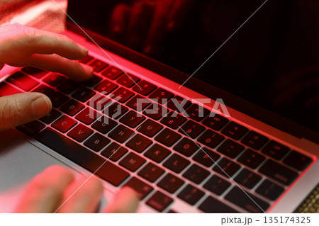 Working on a neon computer keyboard with colored backlighting. Computer video games, hacking, technology, internet concept. Selected focus.  135174325