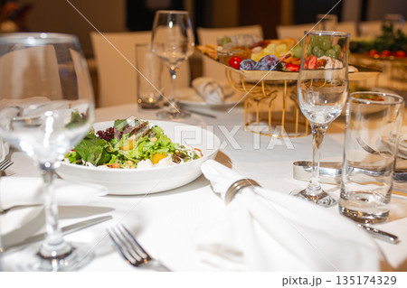 Top view of set table with salad and fruit assortment, elegant table setting for banquet Top view of set table with salad and fruit assortment, elegant table setting for banquet 135174329