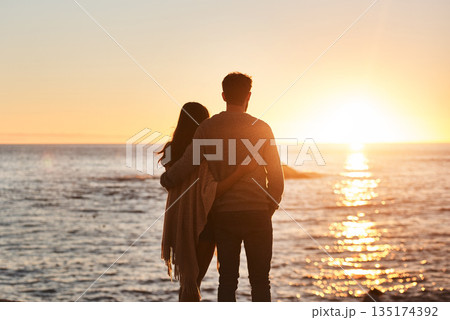 Sunset, beach and back of couple hug in evening on holiday, summer vacation and weekend by ocean. Nature, love and man and woman embrace, hugging and relax for bonding, quality time and peace by sea 135174392