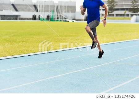 Man, legs and running on track for fitness, workout or exercise of athlete training at the stadium. Leg of male person or runner exercising in run, athletics or sports competition for healthy cardio 135174426