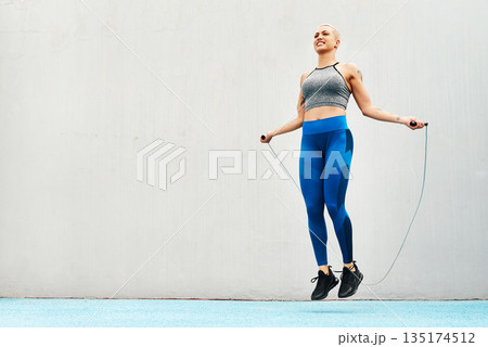 Jump, rope and woman skipping against space in stadium for sports, workout practice and cardio. Performance, health and body with female athlete training on track for strong, mockup and exercise 135174512