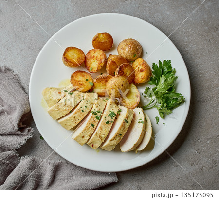 plate of fried boiled potatoes and chicken breast with creamy curry sauce 135175095