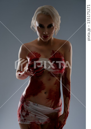 Woman poses with blood body art in a studio setting for artistic expression 135175271