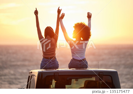 Sunset, women sitting on a car and at the beach with back view for carefree or peace. Freedom or adventure, summer vacation or holiday break and travel with female people at sea happy together 135175477