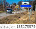 Blank road sign mock-up placed beside a quiet country road on a sunny day 135175575