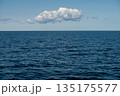 Blue ocean under a clear sky with a single cloud drifting calmly overhead 135175577