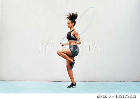 Jump, skipping rope and training with woman in stadium for sports, workout practice and cardio. Performance, health and body with female athlete jumping on track for strong, mockup space and exercise 135175812