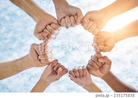 Hands in circle, fist and blue sky, community in collaboration for support and diversity together from below. Teamwork, power hand sign and sunshine, positive group of people in solidarity and huddle 135175838
