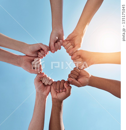 Diversity, fist pump and hands in a circle together for unity, collaboration and teamwork. Solidarity, empowerment and closeup of a group of multiracial people in a round shape by a sky background. Diversity, fist pump and hands in a circle together for unity, collaboration and teamwork. Solidarity, empowerment and closeup of a group of multiracial people in a round shape by a sky background. 135175845