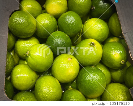 A close-up of fresh green limes in a box. A close-up of fresh green limes in a box. 135176130