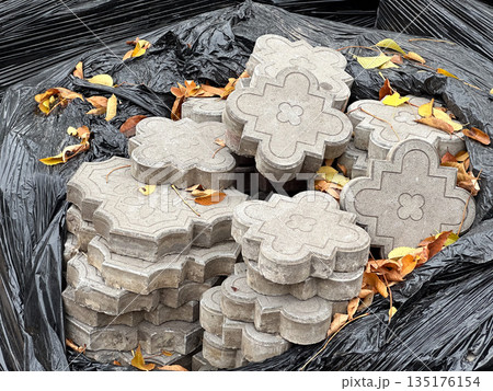 Stack of concrete paving stones with fallen autumn leaves 135176154