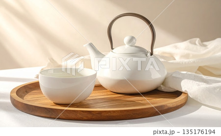 A close-up image of a hot breakfast beverage served in a white porcelain cup and teapot. A close-up image of a hot breakfast beverage served in a white porcelain cup and teapot. 135176194