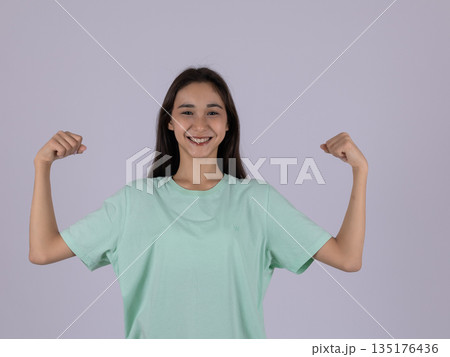 Strong woman in a green shirt showing her biceps Strong woman in a green shirt showing her biceps 135176436