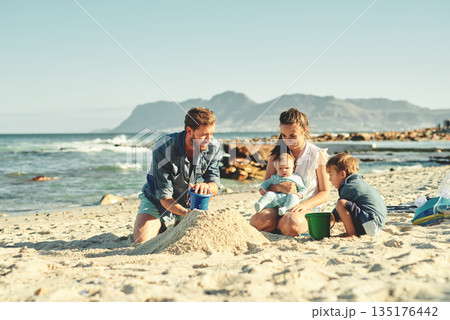 Sandcastle building, parents and children at beach with bonding, love and support. Baby, mom and dad together with kids playing in the sun with mockup space and smile by the ocean and sea with family 135176442