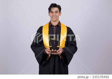 Happy graduate in robe holding award Happy graduate in robe holding award 135176482