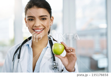 Doctor, portrait and smile of woman with apple for nutrition, healthy diet or wellness. Face, nutritionist and medical professional with fruit for vitamin c, healthcare and food for vegan benefits. 135176658