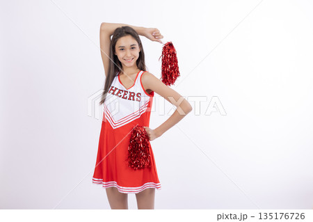 Cheerleader girl in a red skirt posing with pom-poms Cheerleader girl in a red skirt posing with pom-poms 135176726