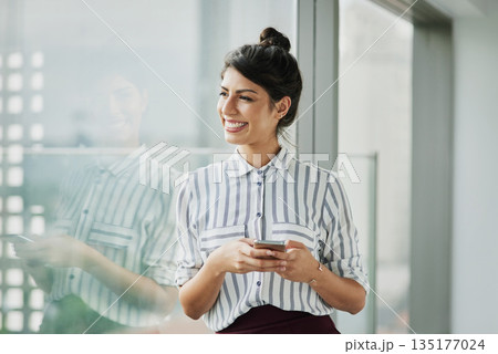 Business woman, thinking and phone with goal at office window with smile and idea. Female employee vision and mobile connection of a worker feeling happy on social media and technology at company 135177024