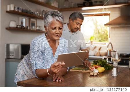 Internet, old woman at kitchen counter with man and tablet, cooking healthy food together in home. Digital recipe, health and senior couple with meal prep, happiness and wellness diet in retirement. 135177140