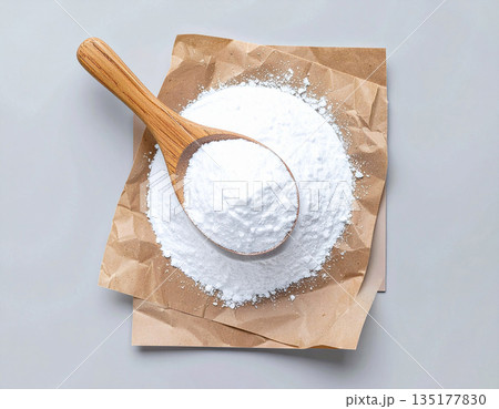Nontoxic agent. Pile of powdered detergent with a wooden spoon on kraft paper on a white background. Nontoxic agent. Pile of powdered detergent with a wooden spoon on kraft paper on a white background. 135177830