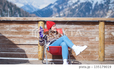 A young pretty woman sitting in the lounger on a background of mountains with bottle of water 135179019