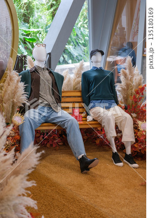 Changi Airport exhibits stylish mannequins on a bench surrounded by vibrant vegetation in Singapore 135180169