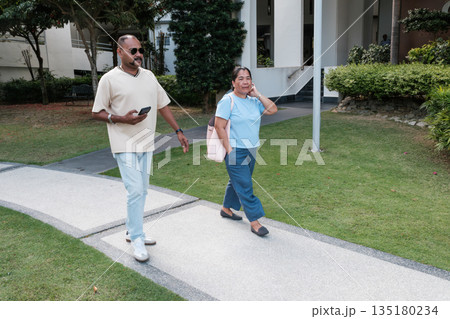 People walk on a path in a grassy area near a building during the day People walk on a path in a grassy area near a building during the day 135180234