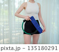 Young woman holding fitness ring and resistance band at home. Concept of home workout, strength training, and healthy lifestyle. Female preparing equipment for online fitness session. 135180291