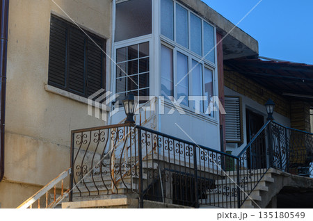 Charming two-story building with a balcony showcasing a serene afternoon in the neighborhood 135180549