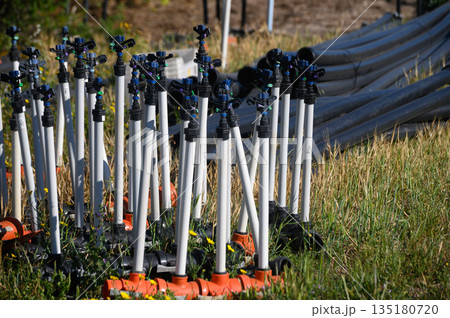 Sprinkler system preparation for efficient irrigation in a vibrant green landscape during sunny summer days Sprinkler system preparation for efficient irrigation in a vibrant green landscape during sunny summer days 135180720