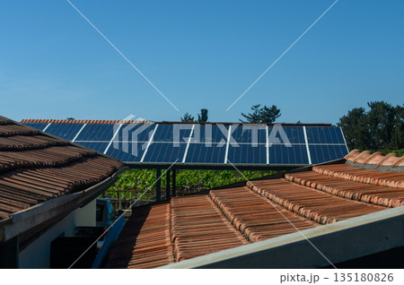 Solar panels on rooftops harnessing renewable energy under a clear blue sky in a sustainable village 135180826