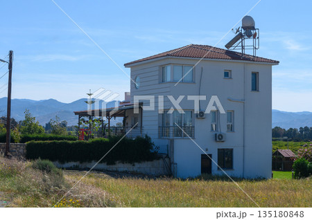 Charming countryside house with satellite dish nestled among green fields on a clear sunny day Charming countryside house with satellite dish nestled among green fields on a clear sunny day 135180848
