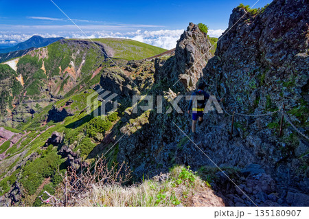 八ヶ岳連峰・横岳の岩稜を行く登山者と硫黄岳・蓼科山の眺め 135180907