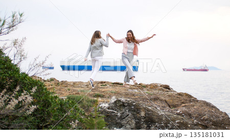 Two young women holding hands walking outdoors 135181031