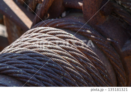 Rustic steel cables wrapped tightly around an ancient winch in a sunlit industrial yard evoke memories labor machinery 135181321