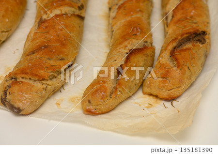 Freshly baked artisanal bread loaves emerge from the oven, showcasing a golden crust and rustic appeal in a cozy kitchen setting 135181390