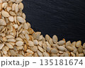 Harvesting the bounty of nature with dried pumpkin seeds on a rustic slate background 135181674