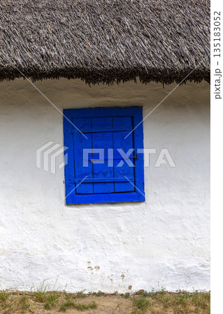 Blue window shutter on traditional thatched roof cottage Blue window shutter on traditional thatched roof cottage 135183052
